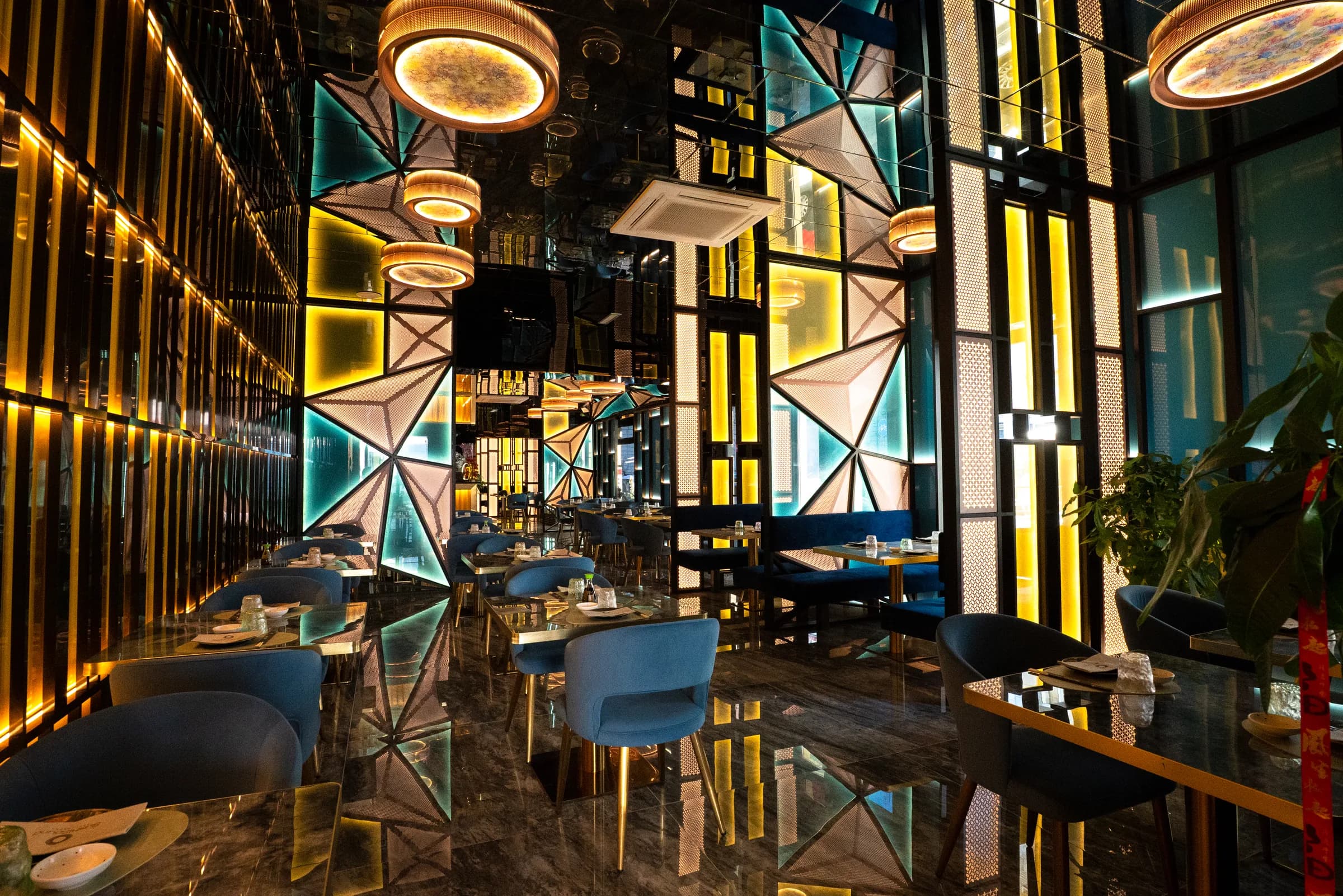 La sala di SushiSound: lampade circolari, pannelli geometrici illuminati e tavoli blu