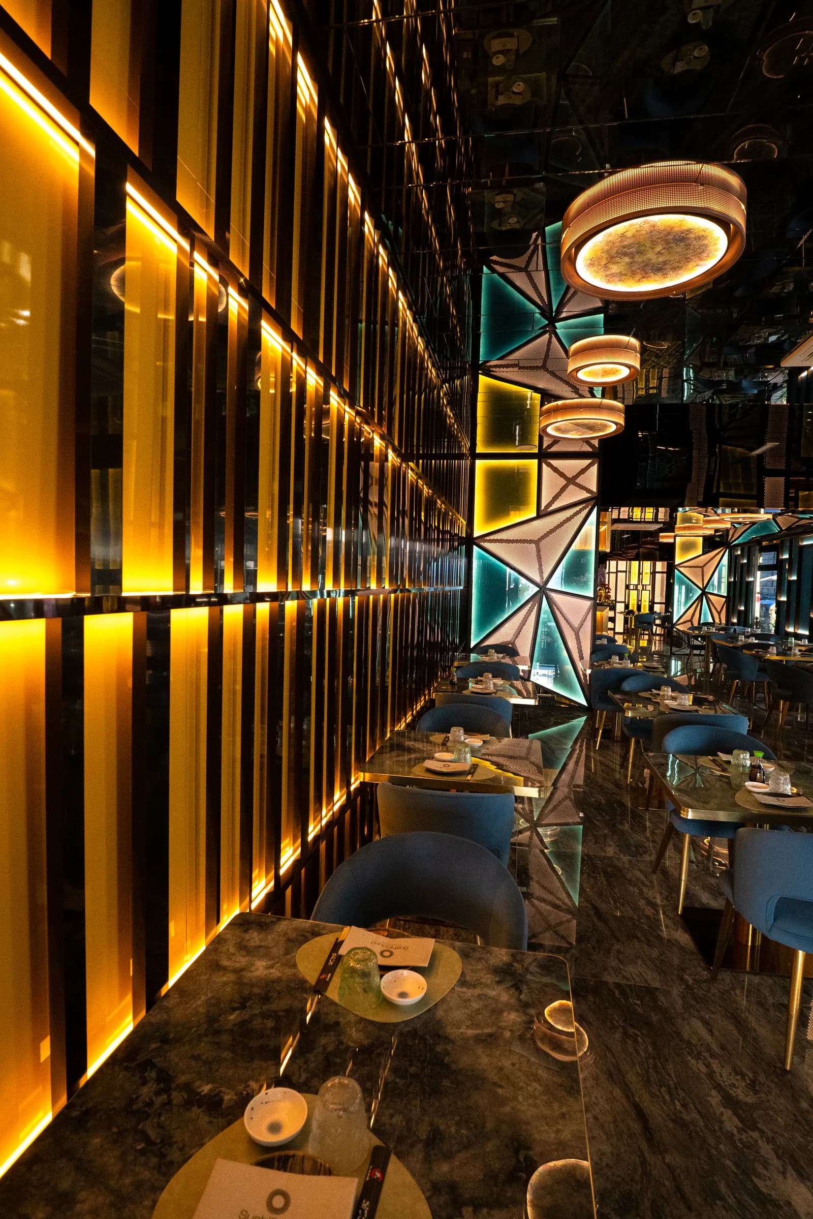 La sala di SushiSound: parete di luci dorate, pannelli geometrici e tavoli in marmo