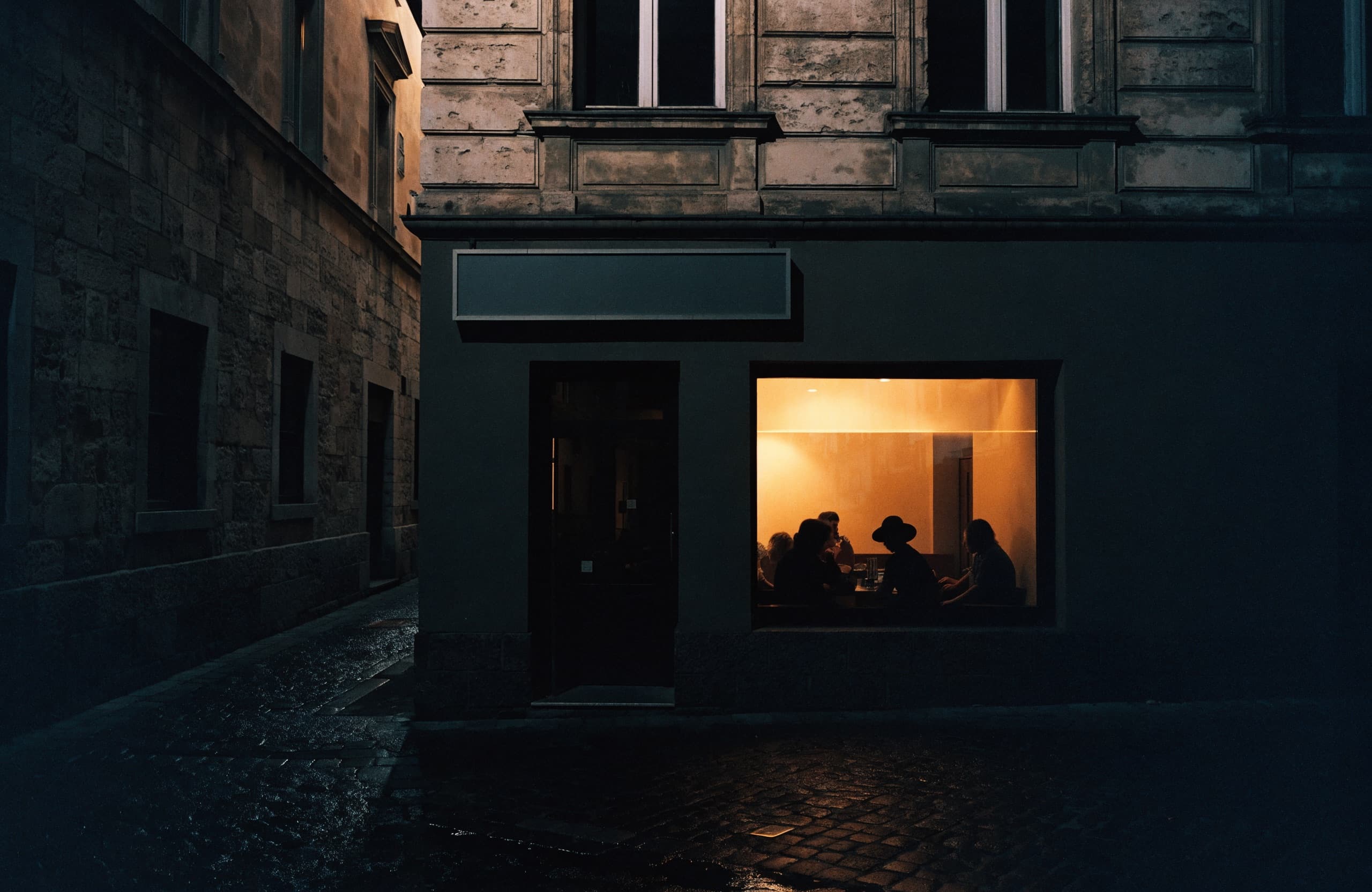 L’ingresso del locale di sera, luce calda sulla strada